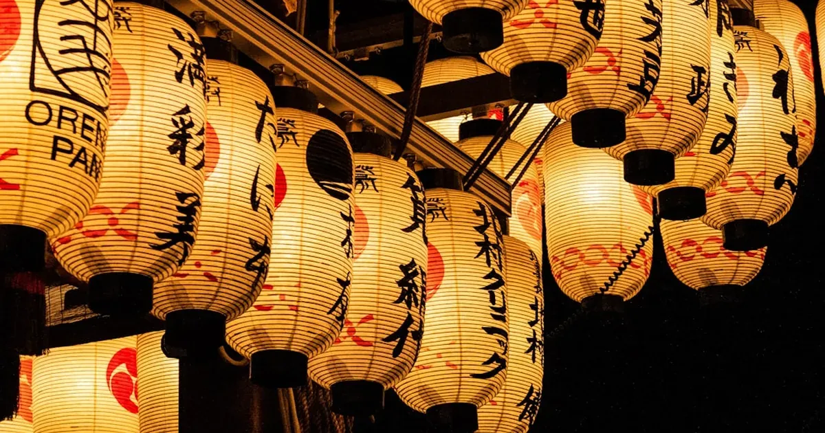 Lantern-lit stone-paved street in Kyoto's Higashiyama district at twilight leading toward a temple gate
