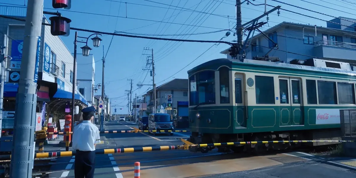 Enoden narrow-gauge coastal tram running through a residential Kamakura street between houses
