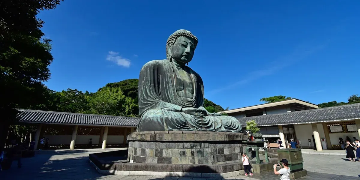 The Great Buddha of Kamakura (Daibutsu) bronze statue in the open air surrounded by trees