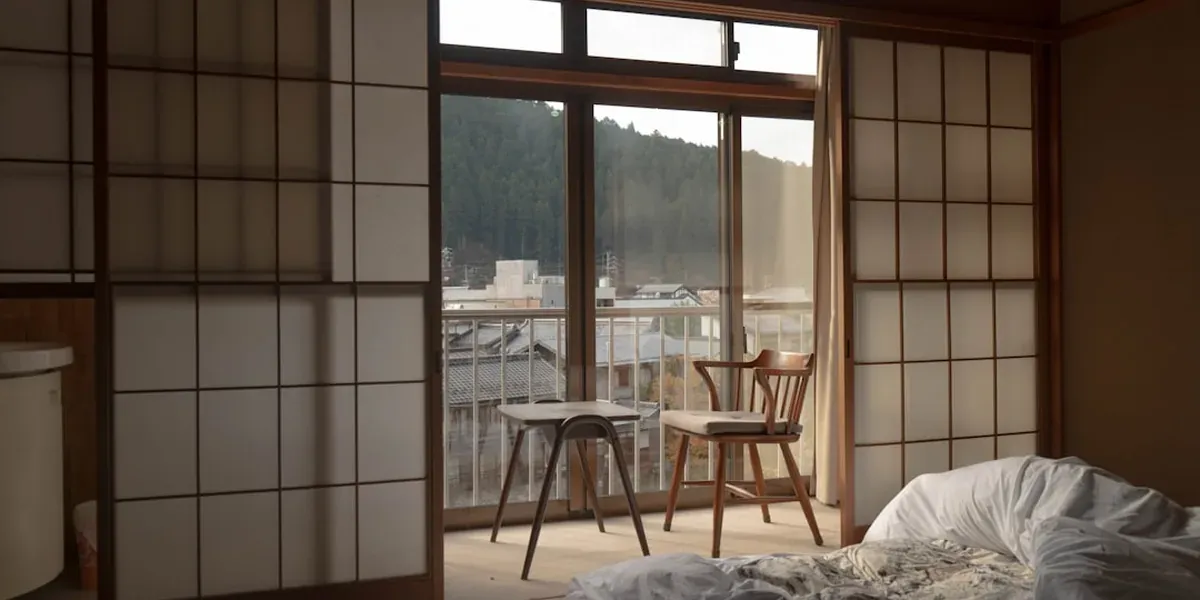 A compact Japanese business hotel room with a clean bed, desk, and city view
