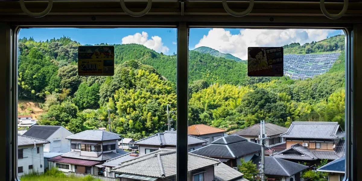 A view from a Japanese train window showing countryside and mountains, illustrating solo day trips