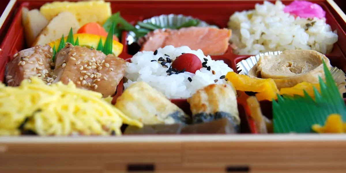 A Japanese bento box with rice, vegetables, and proteins arranged for a family meal