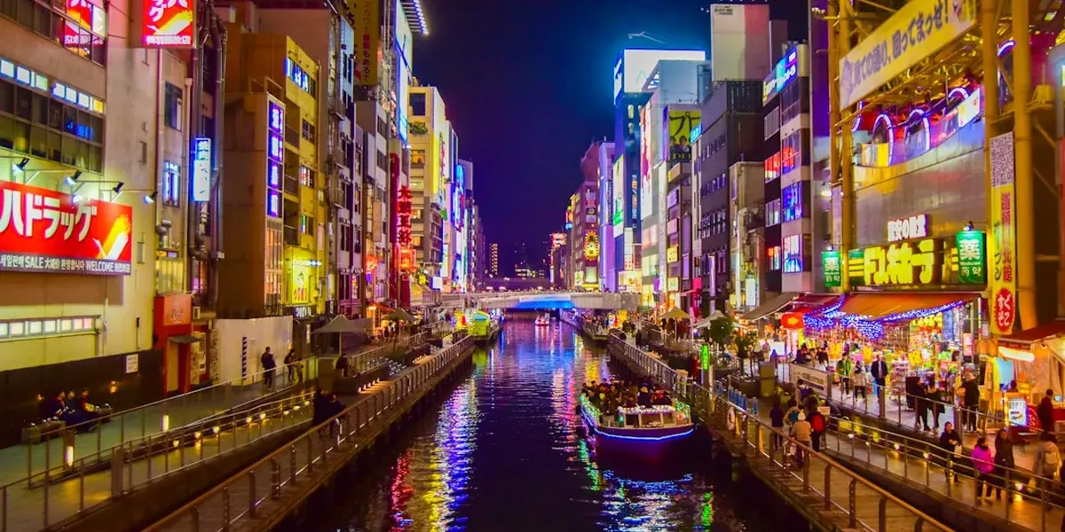 The Dotonbori canal in Osaka at night with bright neon signs reflecting on the water