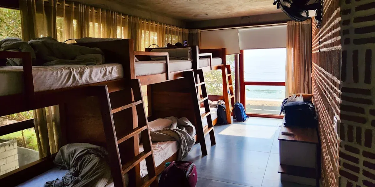 A modern budget hostel dorm room with clean bunk beds and personal lockers
