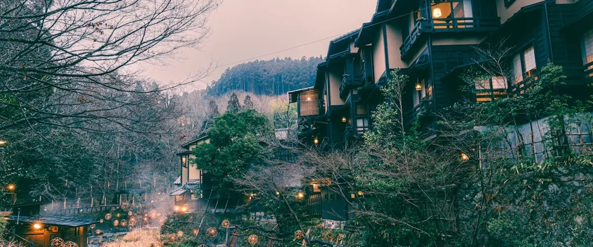 Traditional Japanese ryokan exterior in an onsen town with lanterns and wooden architecture